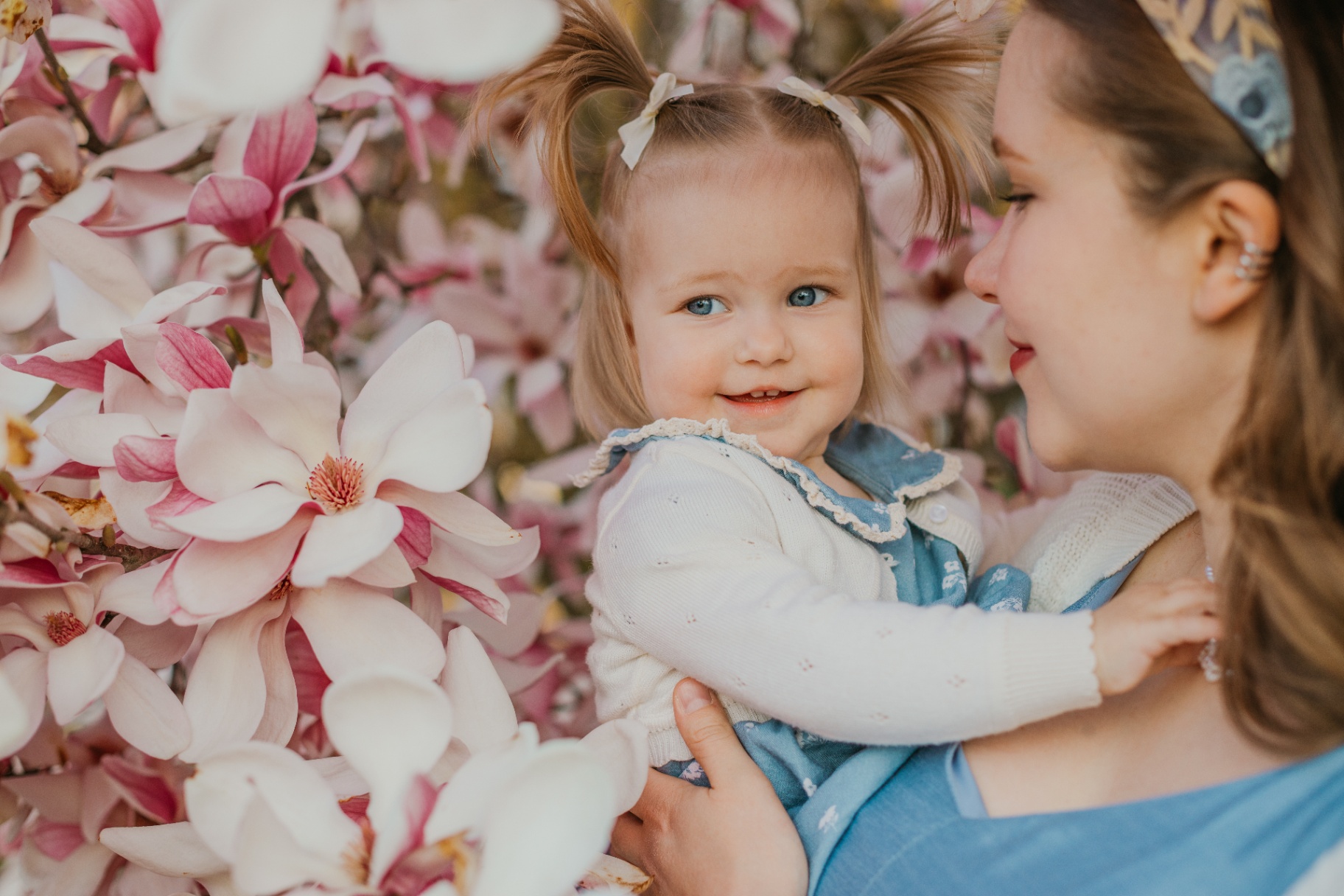 Mother and toddler daughter sharing a moment among magnolia flowers