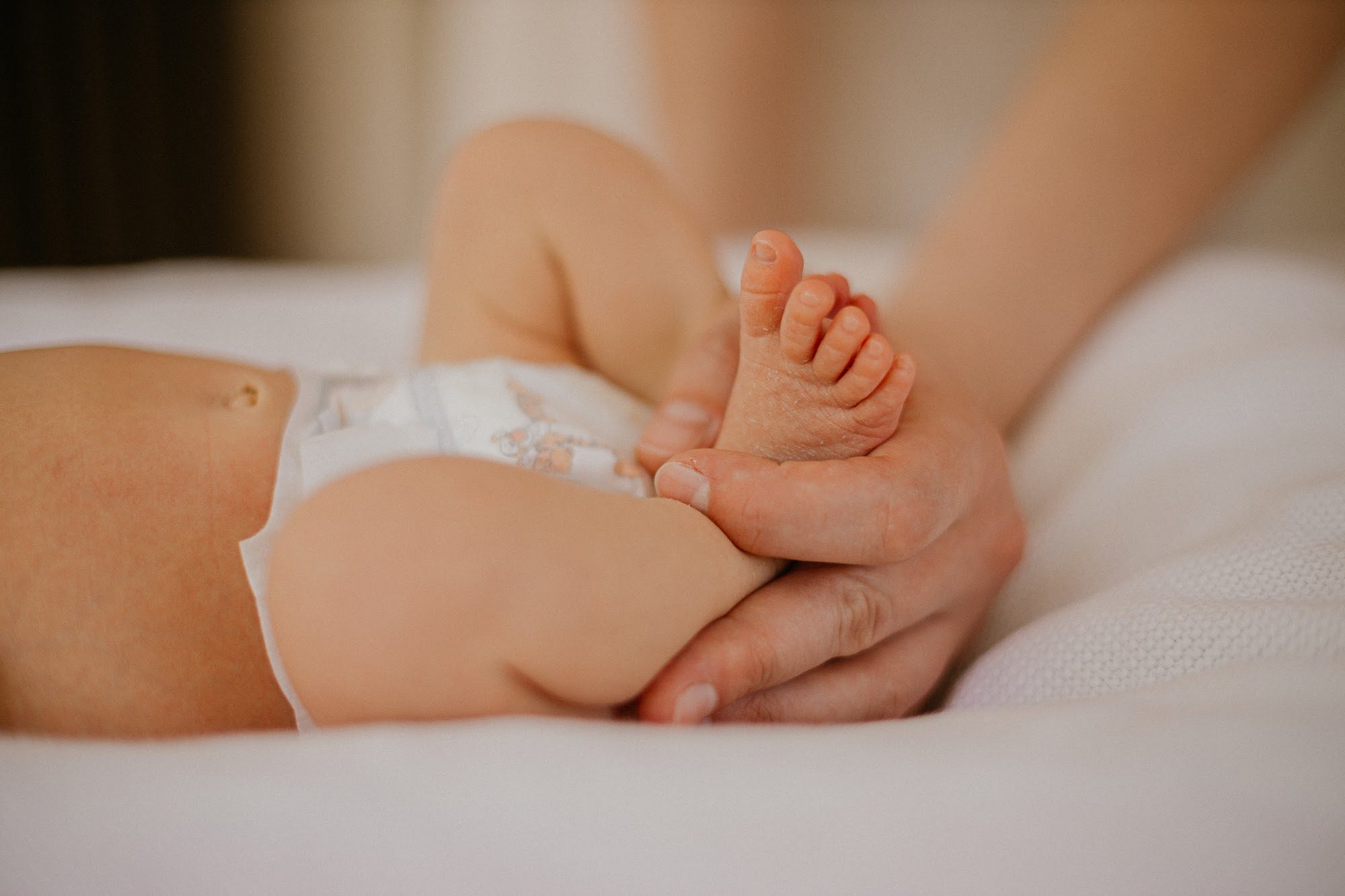Mother holding wrapped newborn by the window — lifestyle newborn session