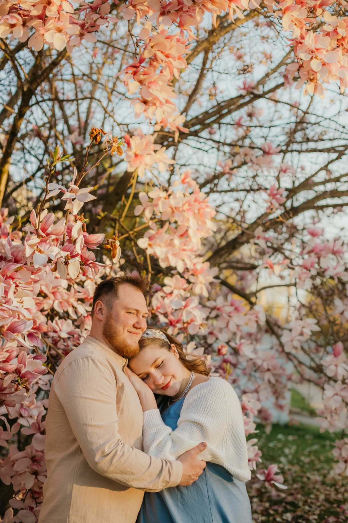 Couple embracing under a magnolia tree in warm spring light