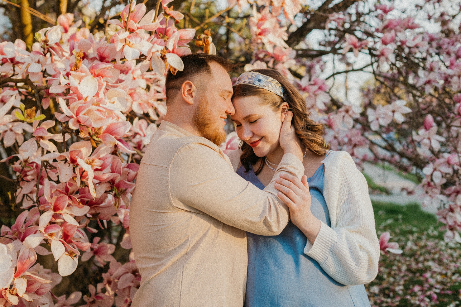 Tender couple portrait beneath magnolia blossoms at golden hour