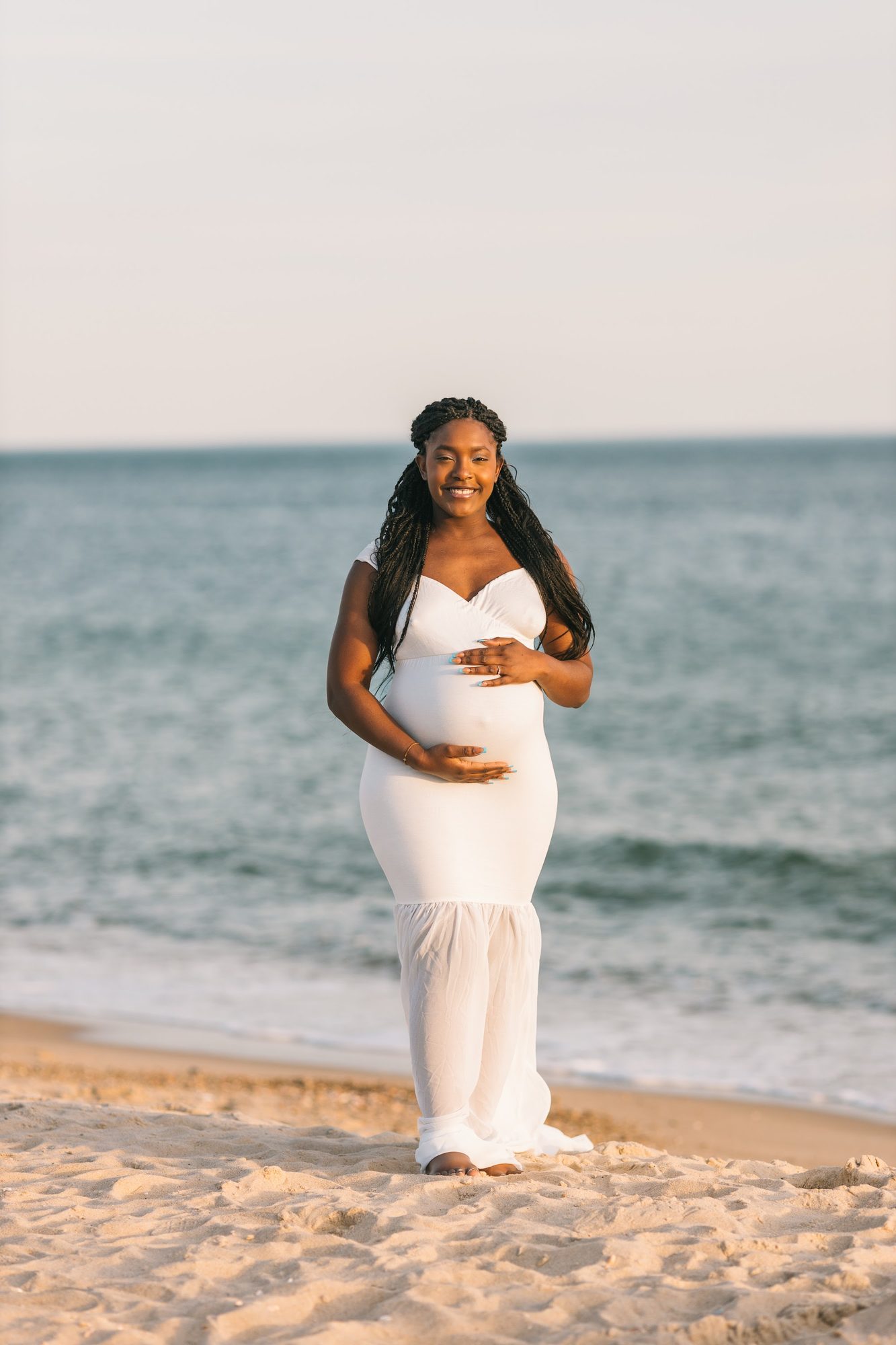 Playful maternity couple lifted on the beach — golden hour
